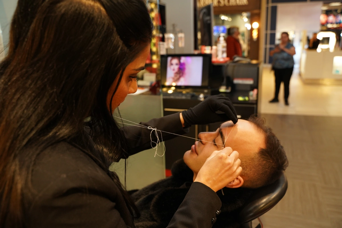 Eyebrow threading service performed on a man